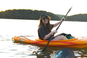 Girl smiling on a kayak in the water with colorful sunscreen on her face